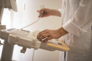 doctor stands at an ultrasound machine with the ultrasound wand in their hand